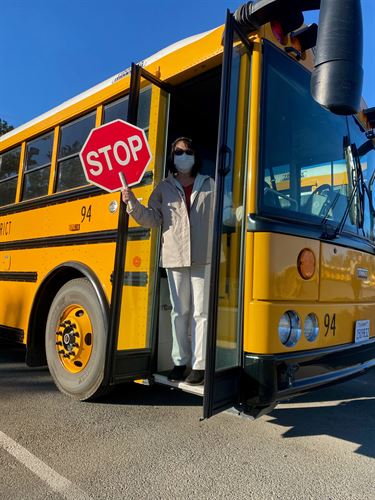 A bus driver holding a stop sign next to a school bus